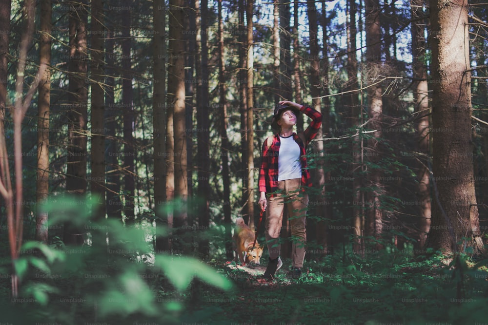 Vista frontal de una mujer joven con un perro en un paseo al aire libre en el bosque en la naturaleza de verano.