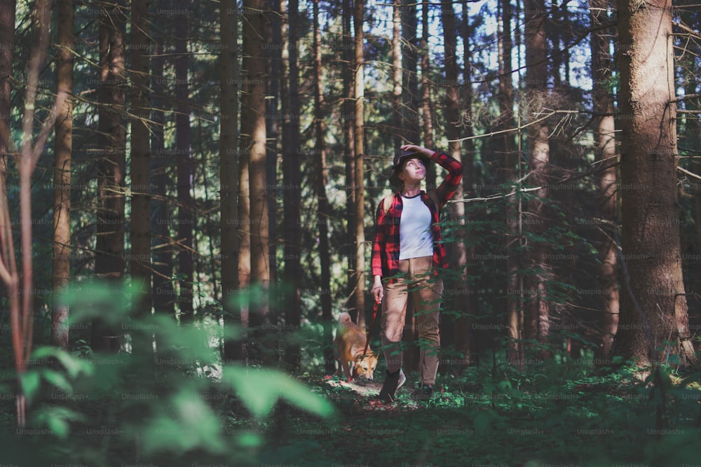 Vue de face d’une jeune femme avec un chien lors d’une promenade à l’extérieur dans la forêt dans la nature estivale.