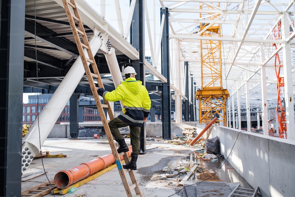 A rear view of man worker outdoors on construction site, working.