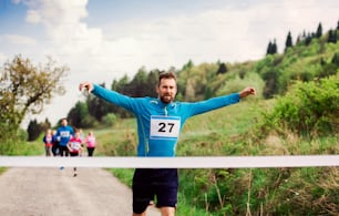 A man runner crossing finish line in a race competition in nature.