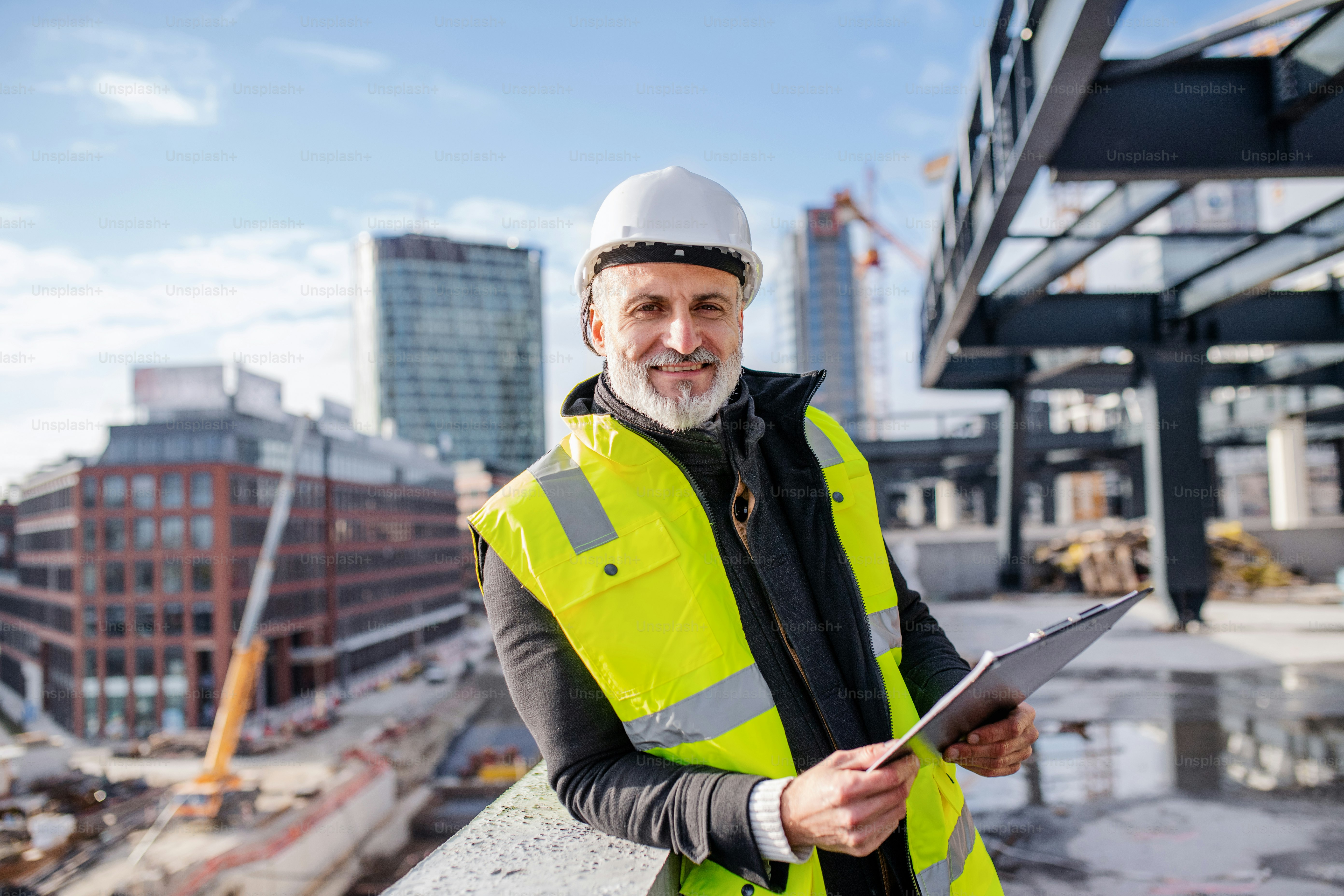 Un ingénieur debout à l’extérieur sur un chantier de construction, regardant la caméra.