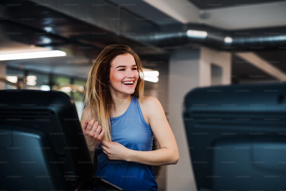 Un retrato de una hermosa joven o mujer haciendo ejercicio cardiovascular en un gimnasio.