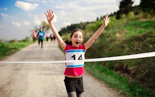 Una pequeña corredora cruza la línea de meta en una competencia de carreras en la naturaleza.