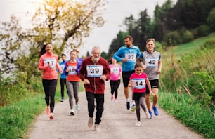 A large group of active multi generation people running a race competition in nature.