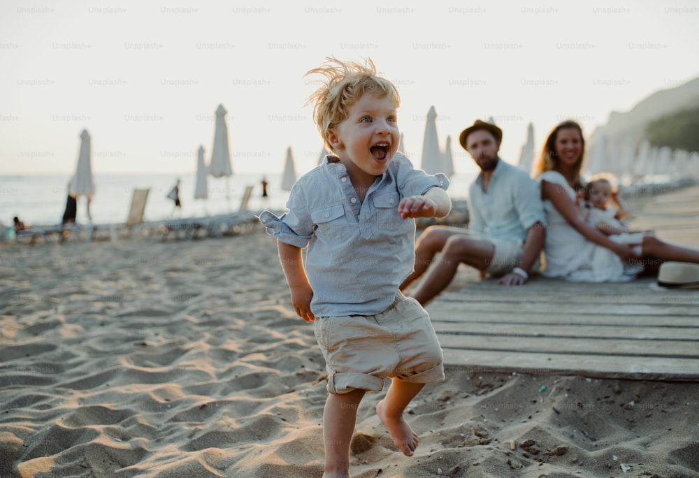 Una familia joven con niños pequeños divirtiéndose en la playa durante las vacaciones de verano.