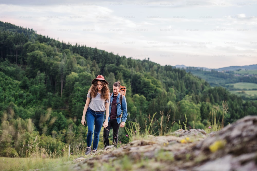 Vista frontale di giovani viaggiatori di coppia turistica con zaini che fanno escursioni nella natura.
