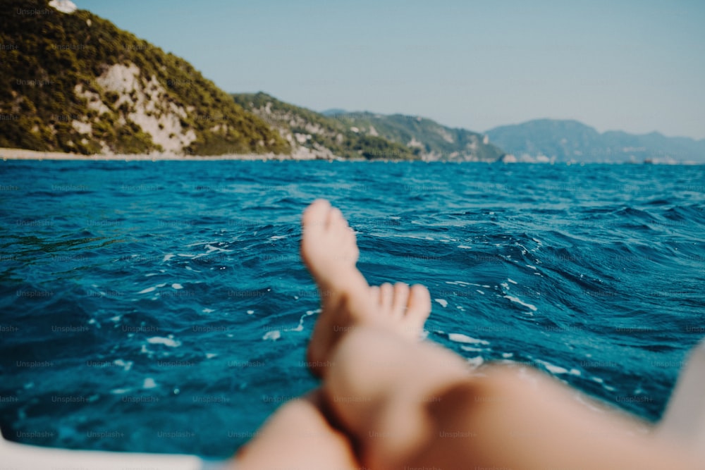 Eine Nahaufnahme weiblicher Beine und Füße am Strand, Sommerurlaubskonzept.
