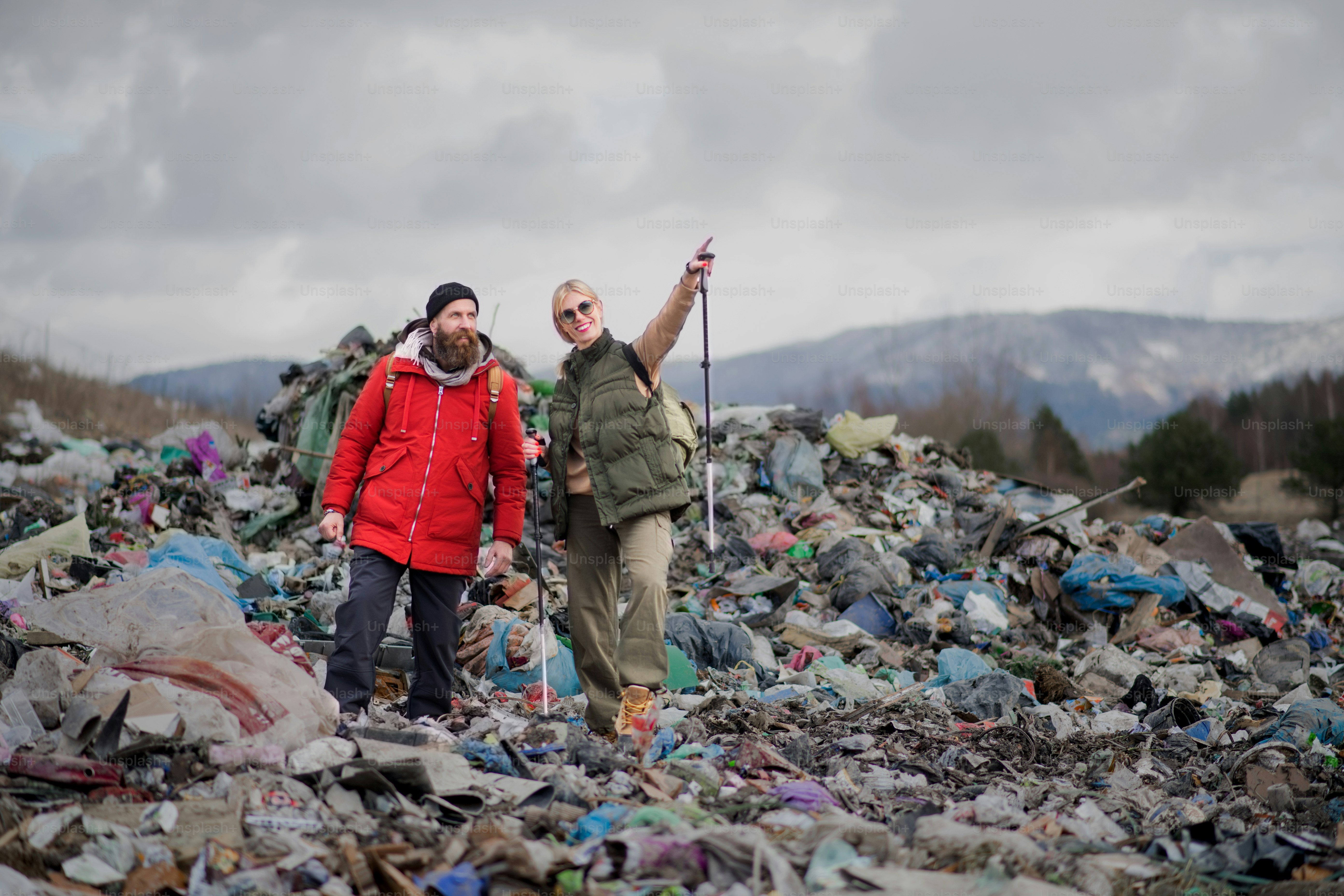 Man and woman hikers on landfill, environmental and pollution concept