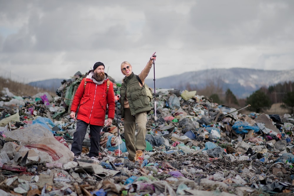 Man and woman hikers on landfill, environmental and pollution concept.