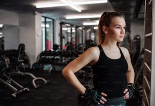 A portrait of a beautiful young girl or woman standing in a gym, hands on hips.