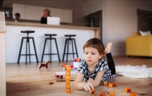 A small girl playing with blocks on the floor at home.