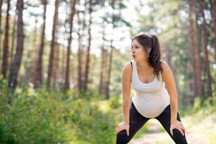 Front view portrait of happy pregnant woman outdoors in nature, doing exercise.