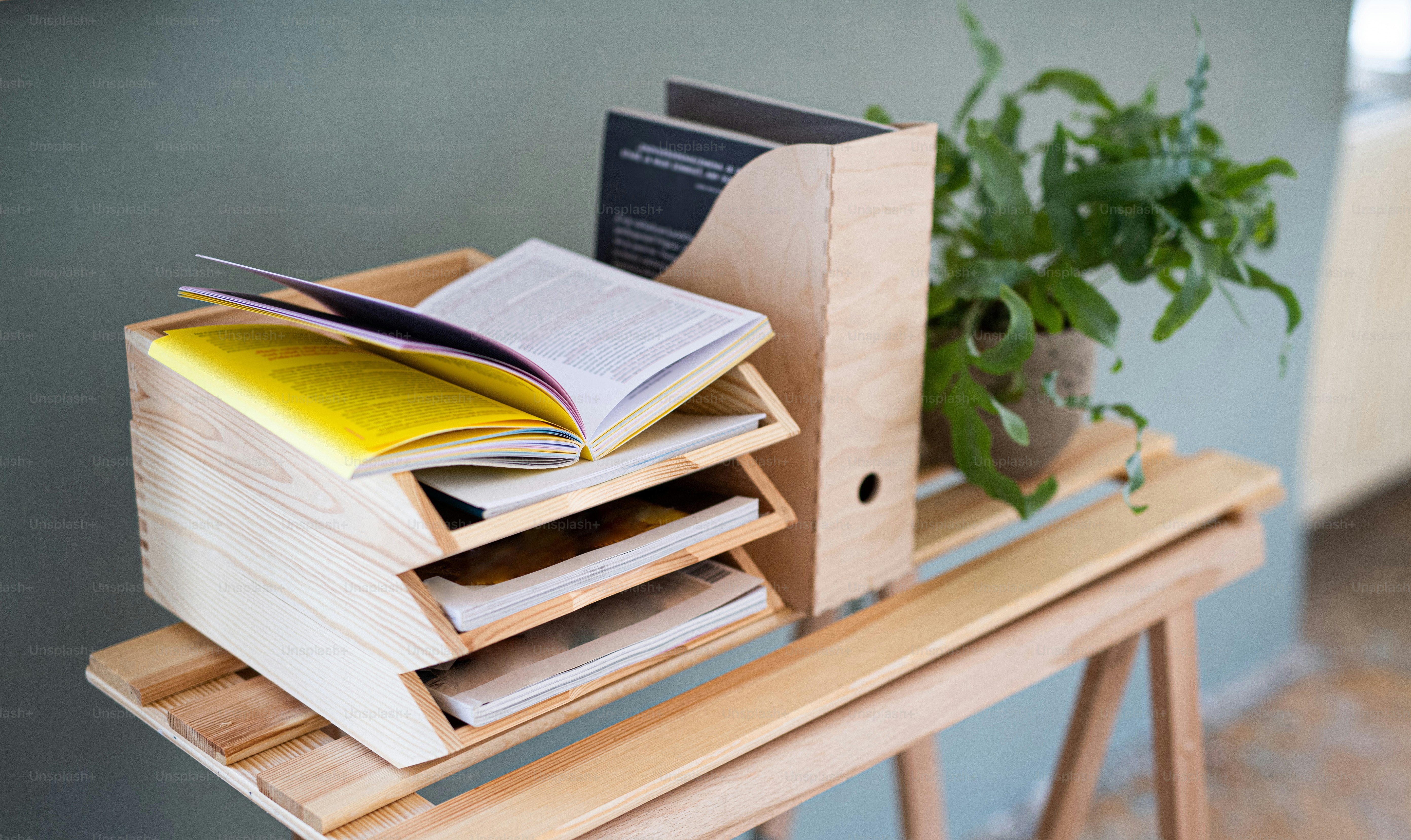 Paper and document wooden tray holders and organisers on desk with plant, natural decor concept.