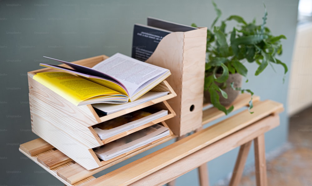 紙と書類の木製トレイホルダーと植物、自然な装飾のコンセプトを持つ机の上のオーガナイザー。