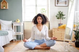 Retrato de uma jovem relaxada dentro de casa, fazendo exercício de yoga.