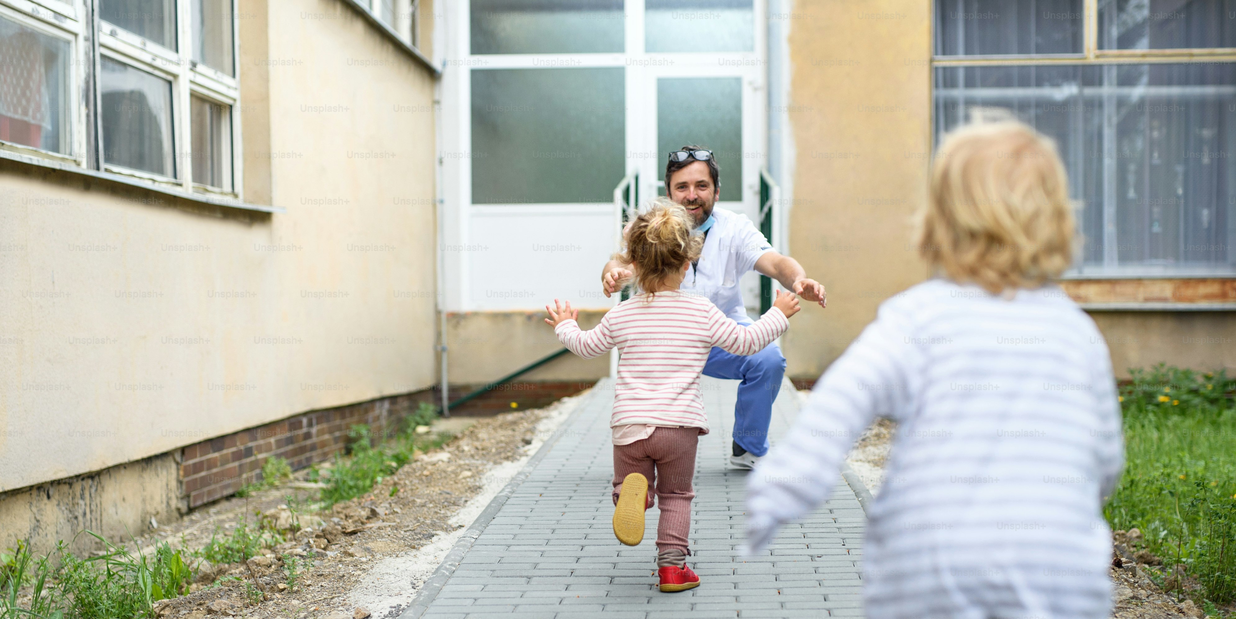 Bambini felici che corrono a salutare il padre medico davanti all'ospedale, fine del concetto di coronavirus.