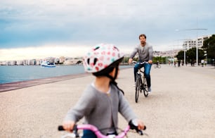 A father and small daugther with bicycles outdoors cycling on beach.