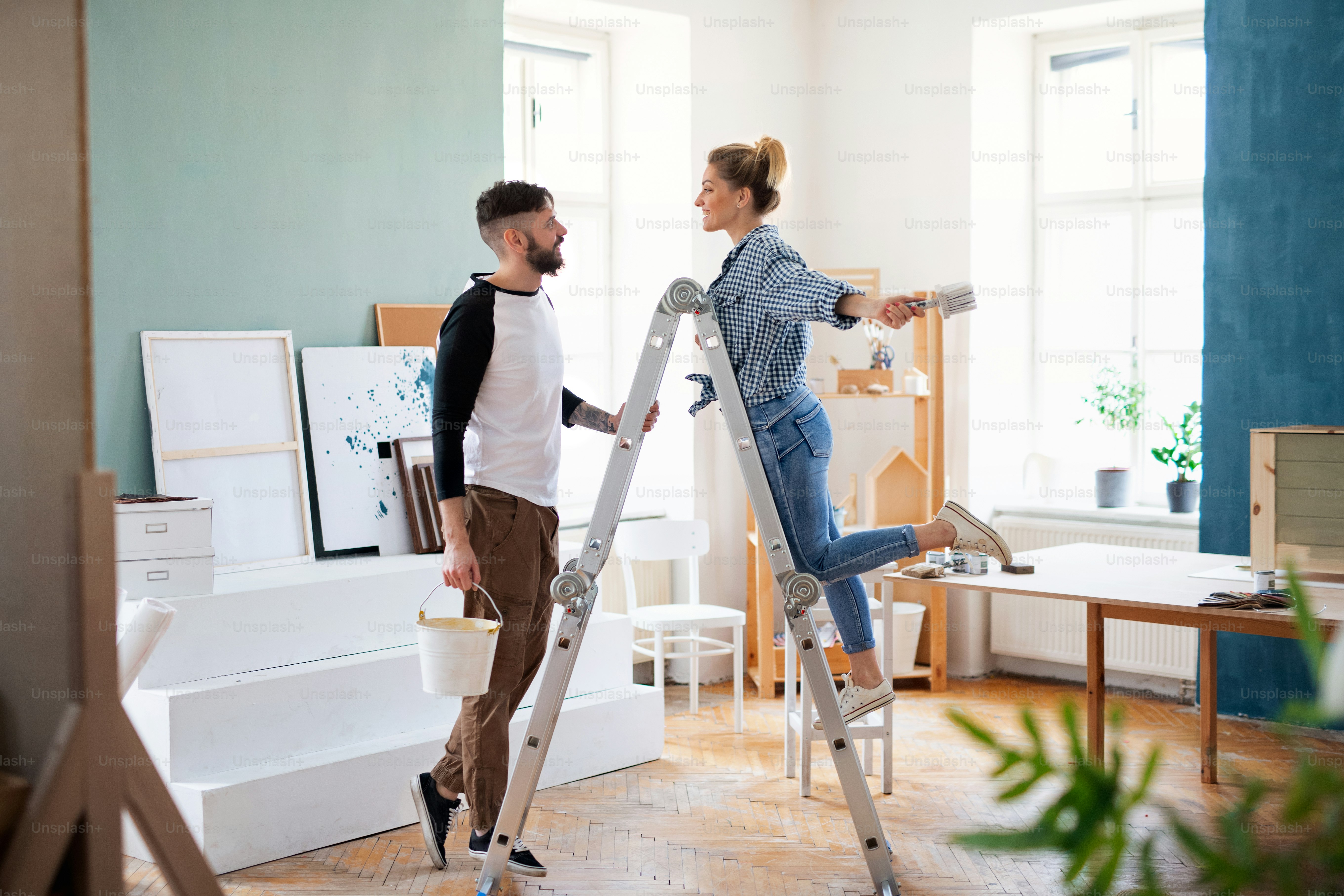 Happy mid adults couple painting furniture indoors at home, relocation and diy concept