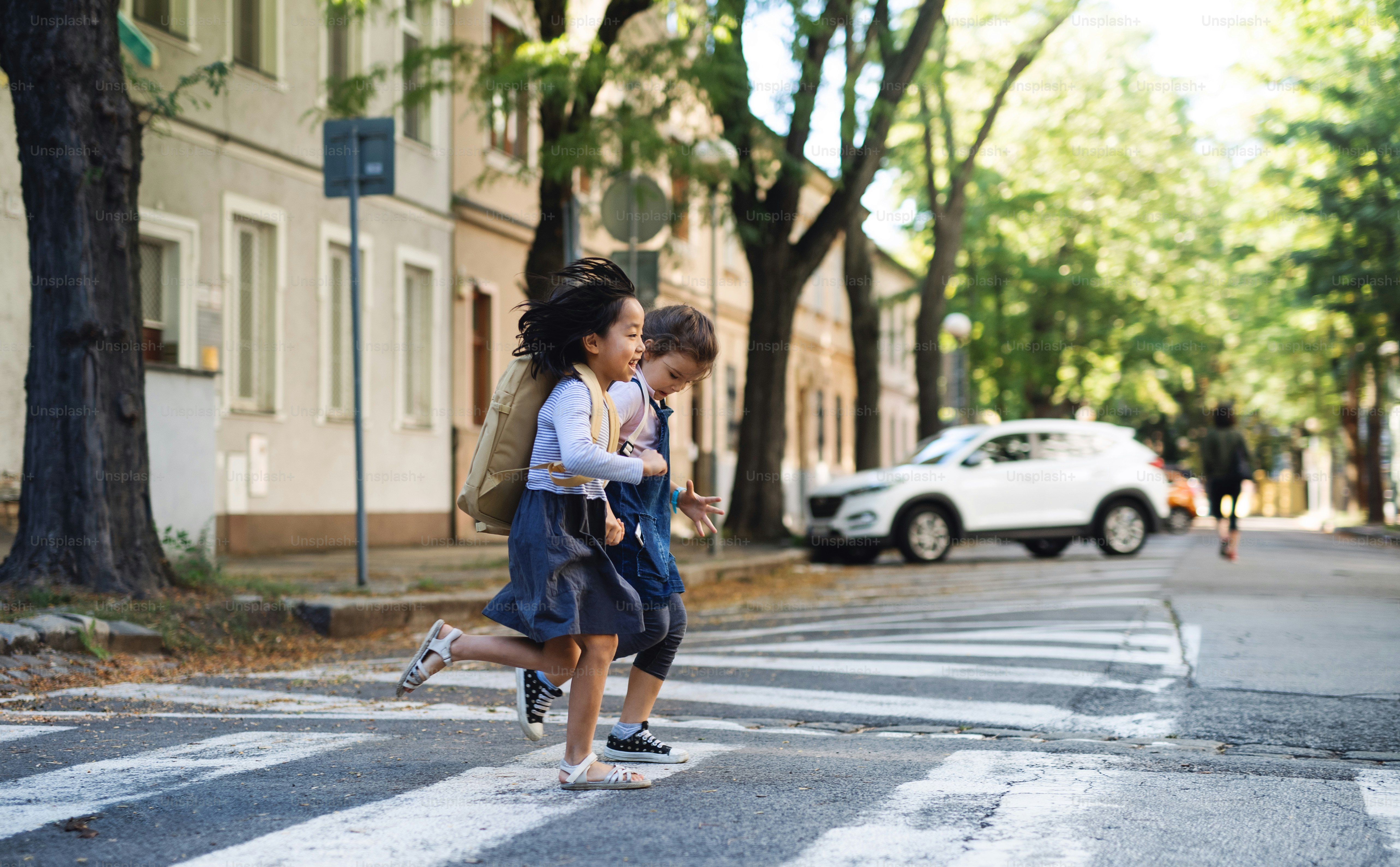 Niñas pequeñas alegres que cruzan la calle al aire libre en la ciudad, concepto de coronavirus.