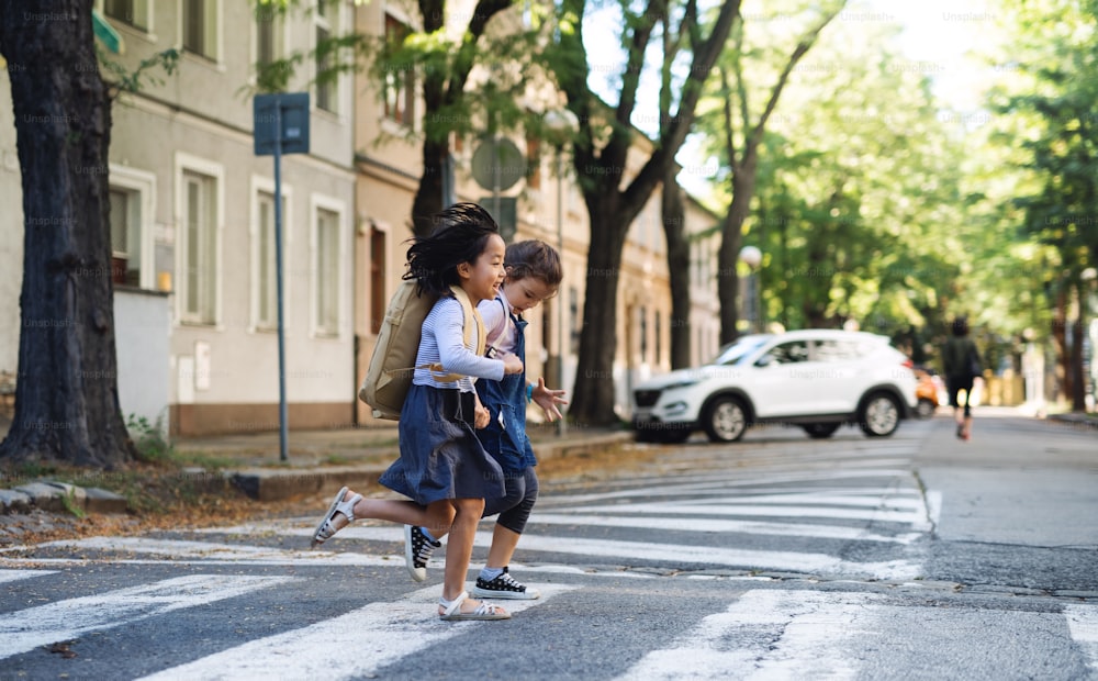 Petites filles joyeuses traversant la rue à l’extérieur en ville, concept de coronavirus.