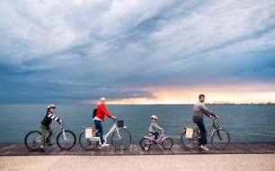 Young family with small children and bicycles outdoors on beach, cycling.