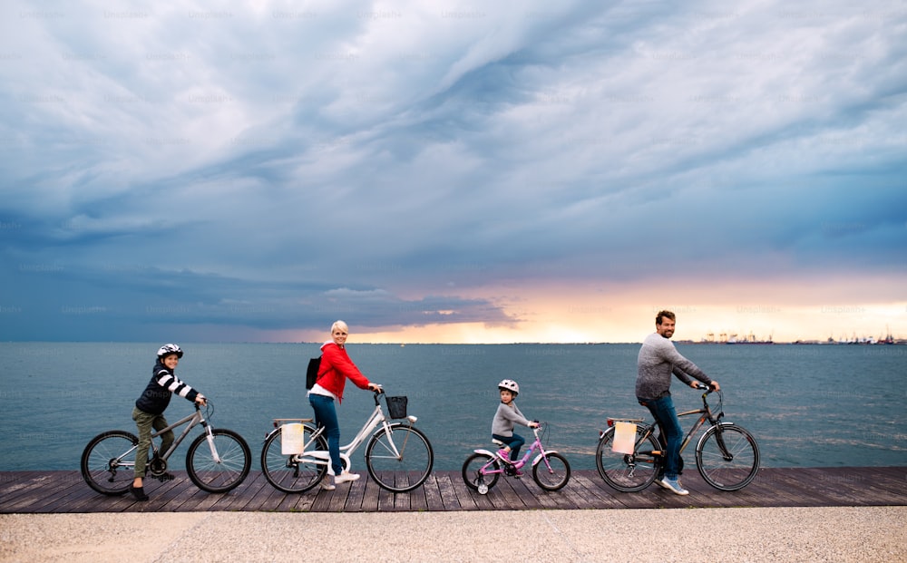 Young family with small children and bicycles outdoors on beach, cycling.