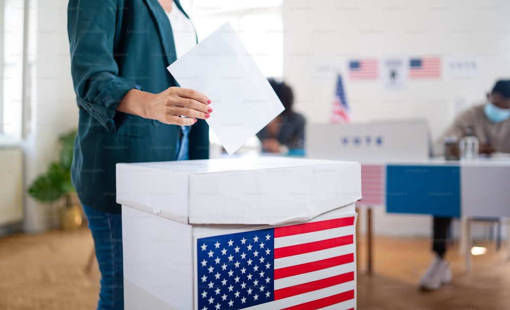 投票箱に一票を入れる見分けがつかない女性、アメリカの選挙とコロナウイルスのコンセプト。