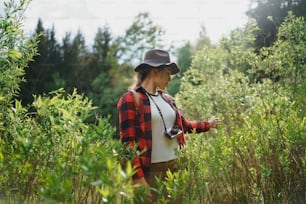 Front view of young woman with camera on a walk in forest in summer nature.