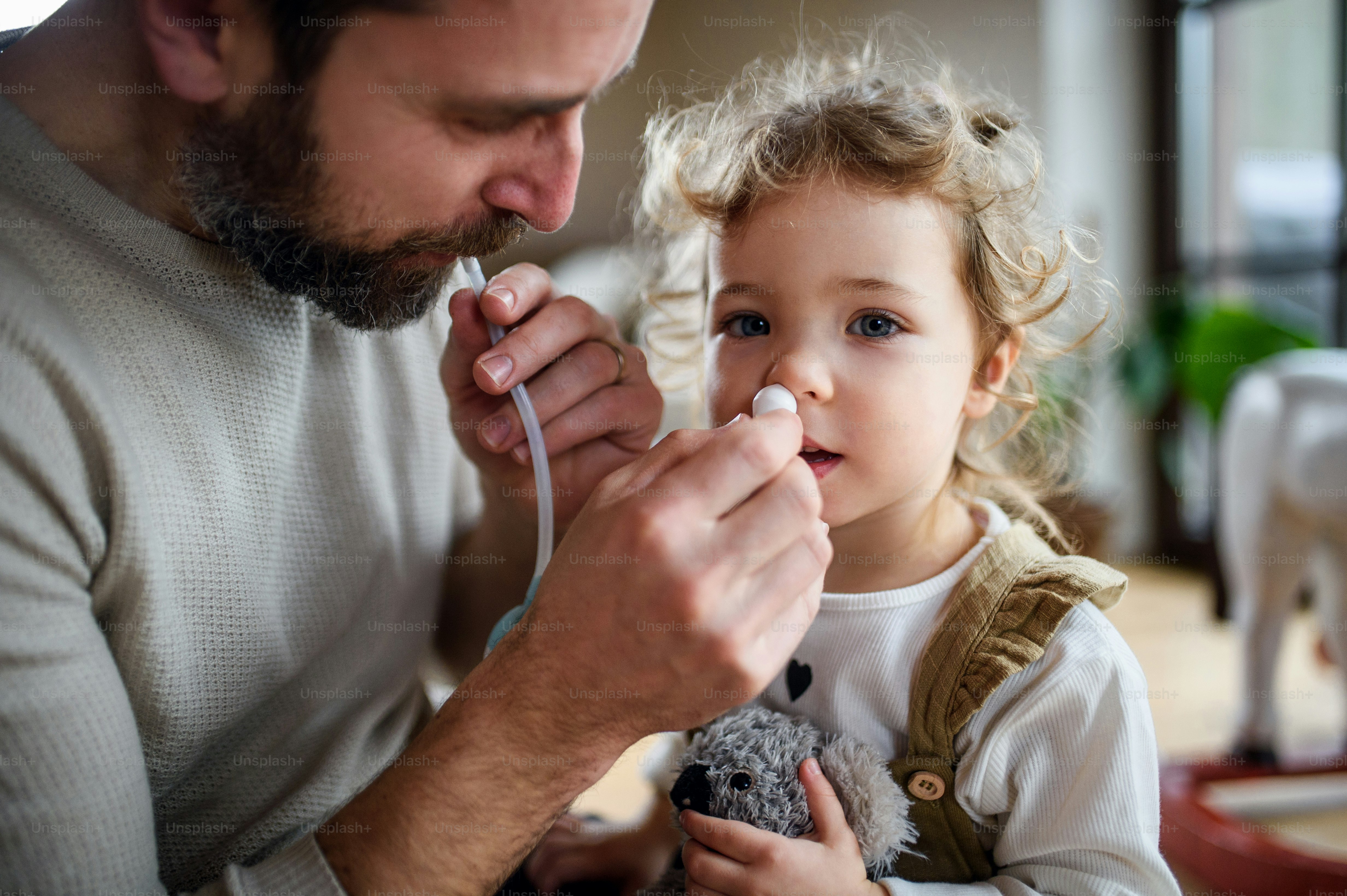 Père mûr avec sa petite fille malade à l’intérieur à la maison, à l’aide d’un mouche-bébé.