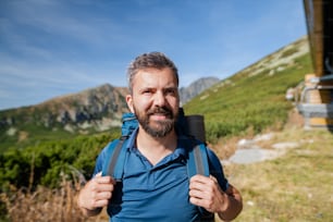 Uomo maturo con zaino che fa escursioni in montagna in estate, riposando.