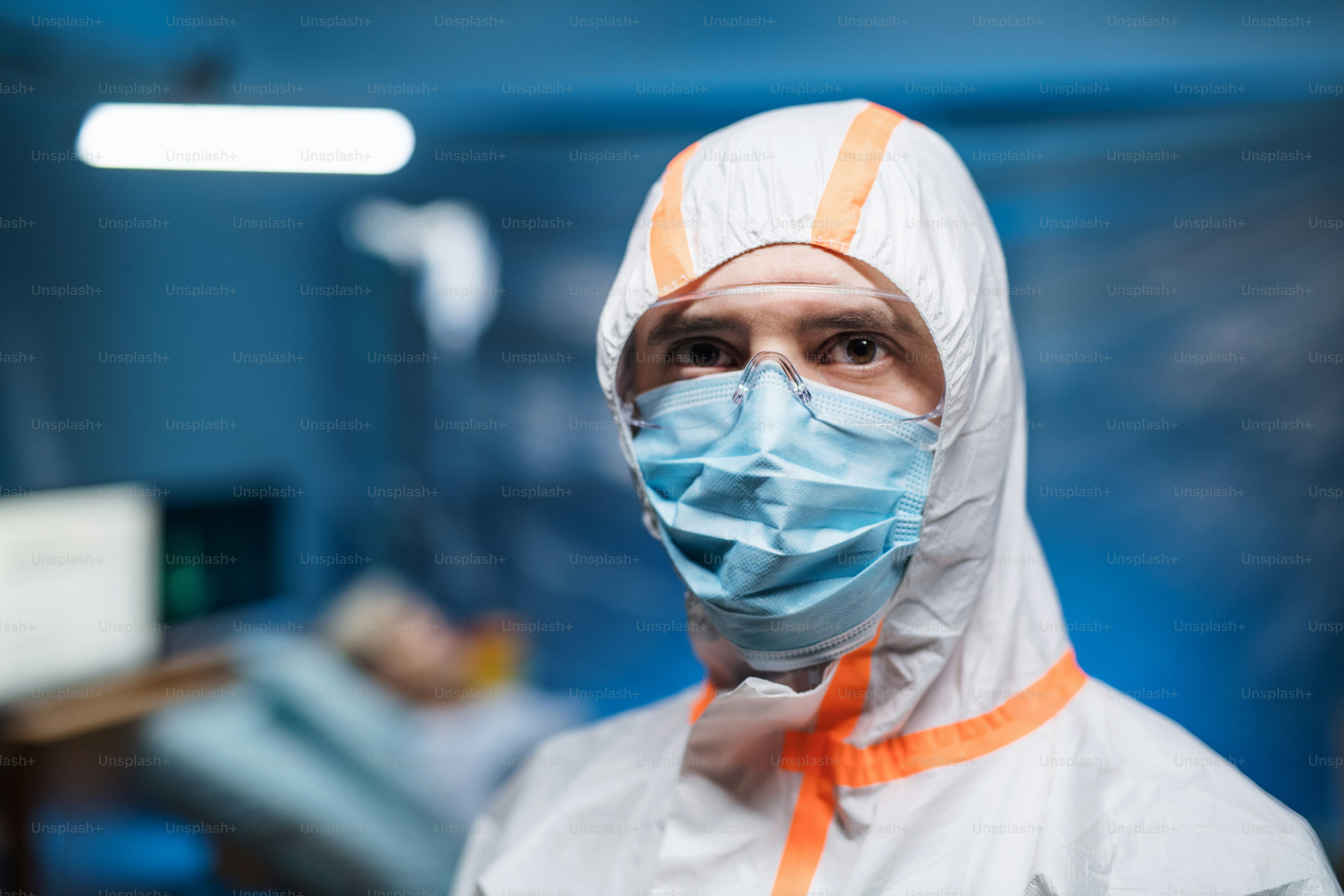 Front view of man with protective suit and face mask indoors, coronavirus concept.