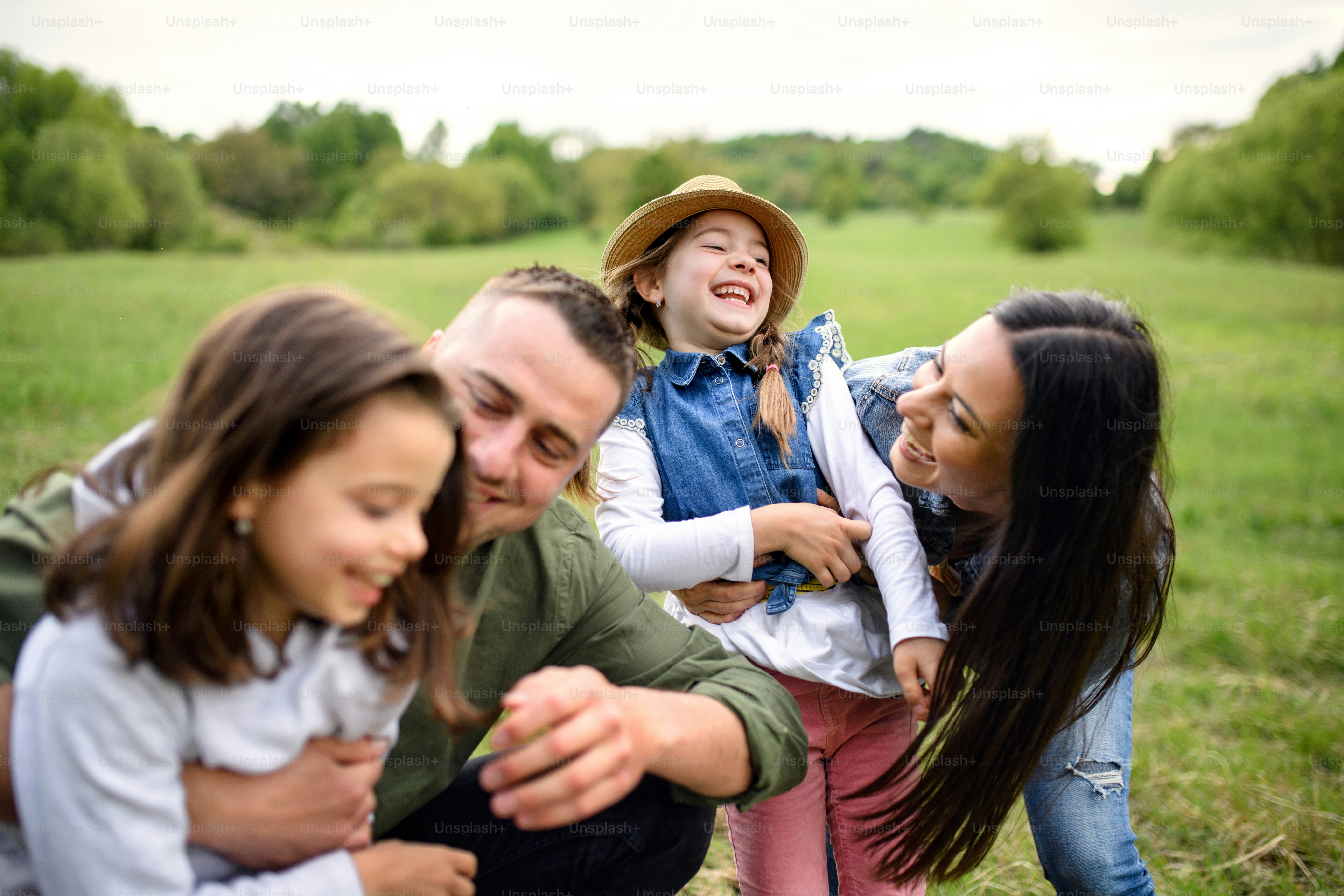 Front view of happy family with two small daughters having fun outdoors ...