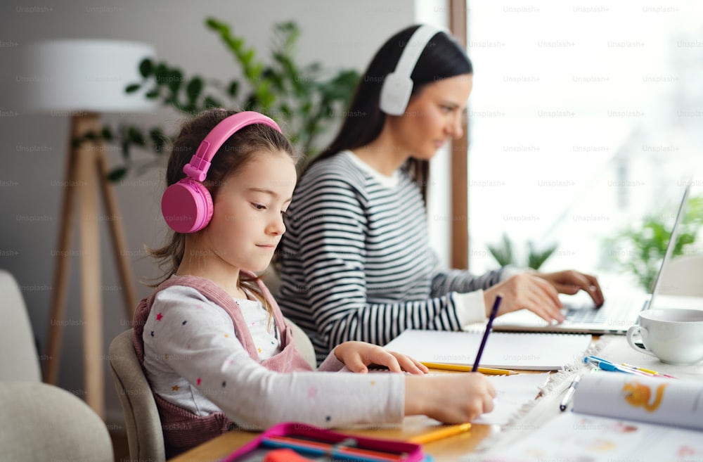 Mother with school girl indoors at home, distance learning and home office concept.