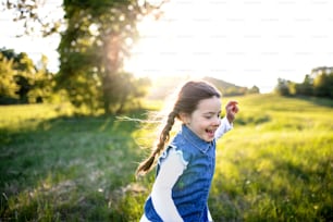 Ritratto di bambina allegra che corre all'aperto nella natura primaverile, ridendo.
