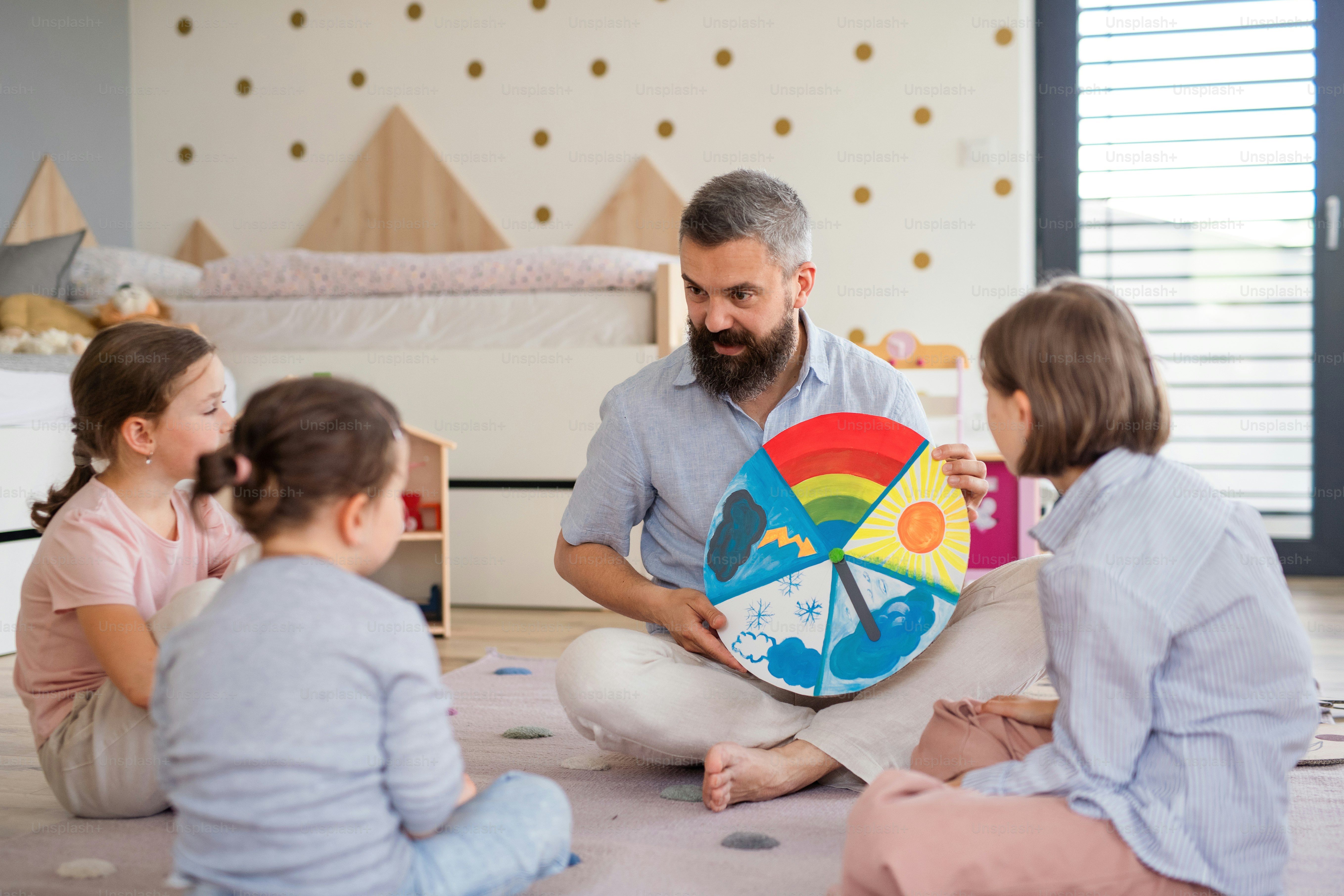 A father with three daughters indoors at home, playing on floor