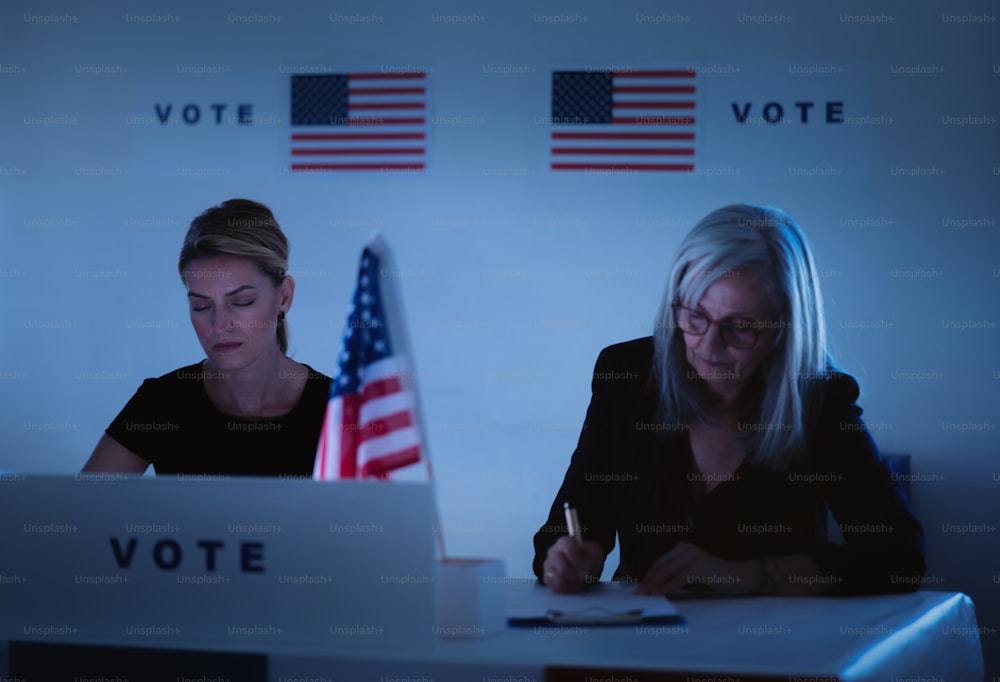 Müde weibliche Mitglieder der Wahlkommission in Wahllokal zur Nachtzeit, USA Wahlen.