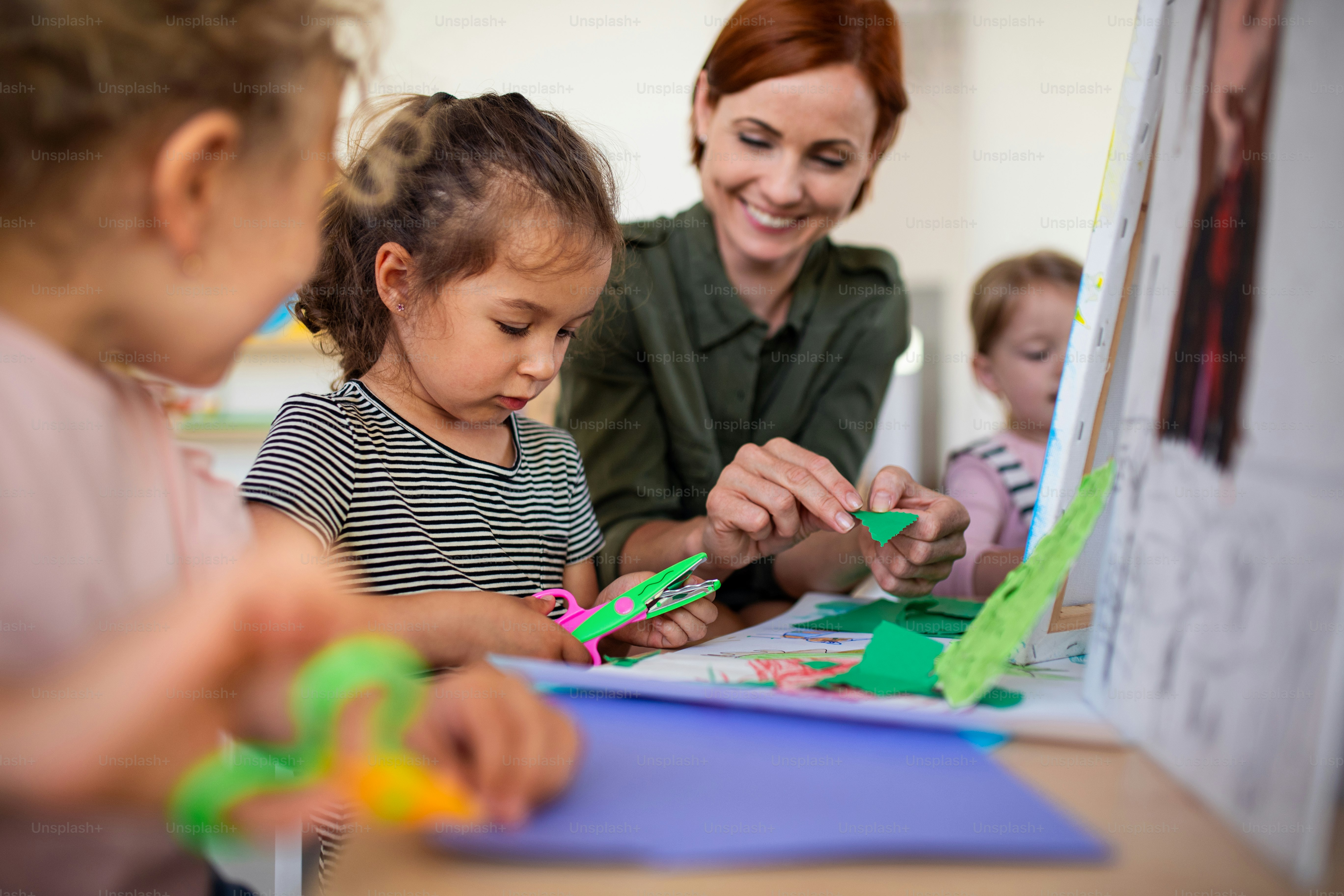 Un grupo de pequeños niños de guardería con maestro en el interior del aula, concepto de arte y artesanía