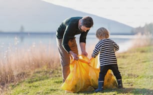 Reifer Vater mit kleinen Kindern, der im Garten arbeitet, nachhaltiges Lifestyle-Konzept.