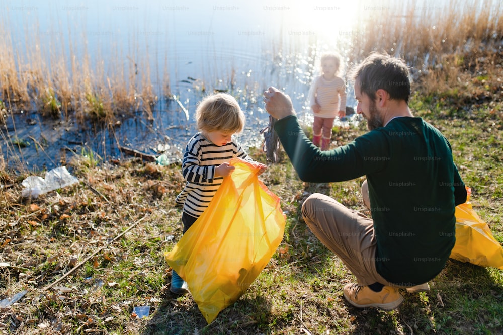 Padre maduro con niños pequeños que trabajan al aire libre en el jardín, concepto de estilo de vida sostenible.