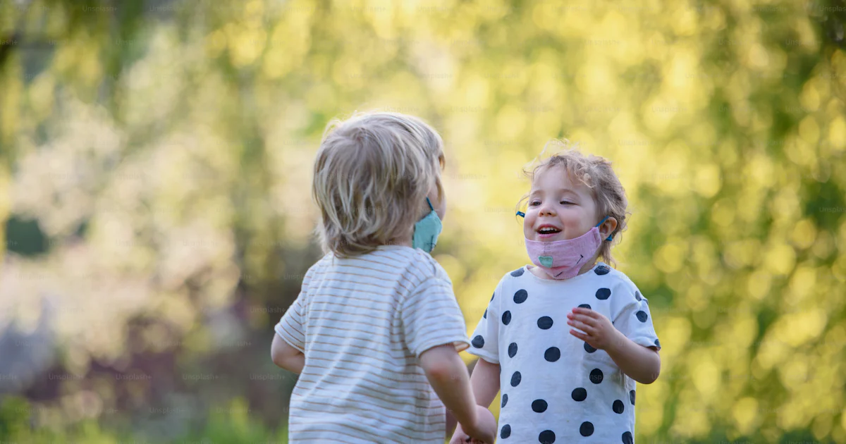 Small children with face masks playing outdoors in countryside ...