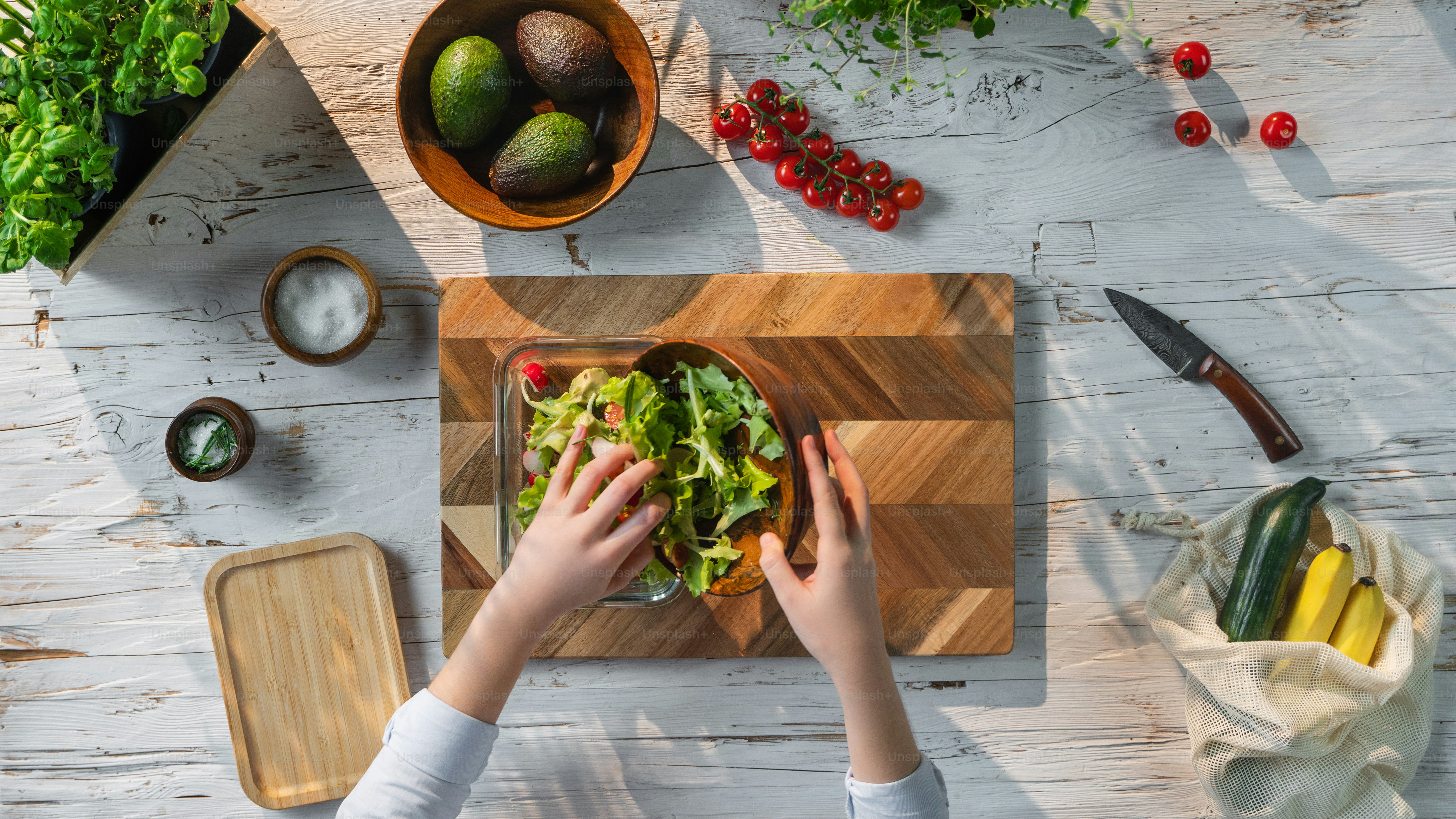 Una vista superior de una mujer irreconocible preparando ensalada de verduras, estilo de vida sostenible.