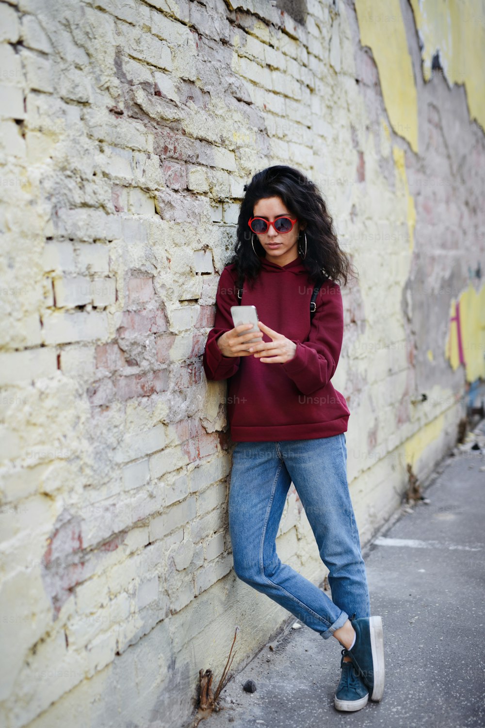 A portrait of young woman standing outdoors on street in city, using smartphone.