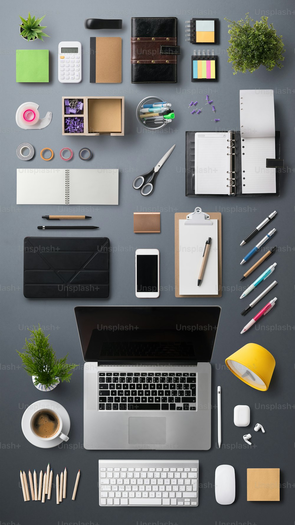 灰色の背景にラップトップ、タブレット、スマートフォン、備品を備えたフラットレイトップビューオフィスデスクワーキングスペース。