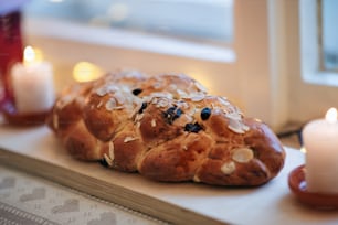 Close-up of sweet Christmas bread with raisins and flaked almonds on window sill.