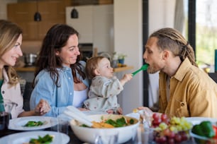 Una felice famiglia multigenerazionale in casa a mangiare un pranzo sano.
