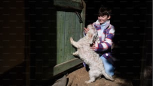 Pauvre petite fille heureuse jouant avec un chien à l’extérieur devant la maison, concept de pauvreté.