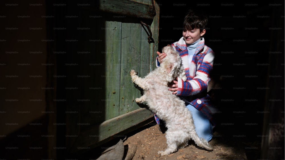 Povera bambina felice che gioca con il cane all'aperto davanti alla casa, concetto di povertà.