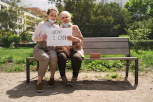 Portrait of young woman with a grandmother outdoors in city, life after covid-19 vaccination.