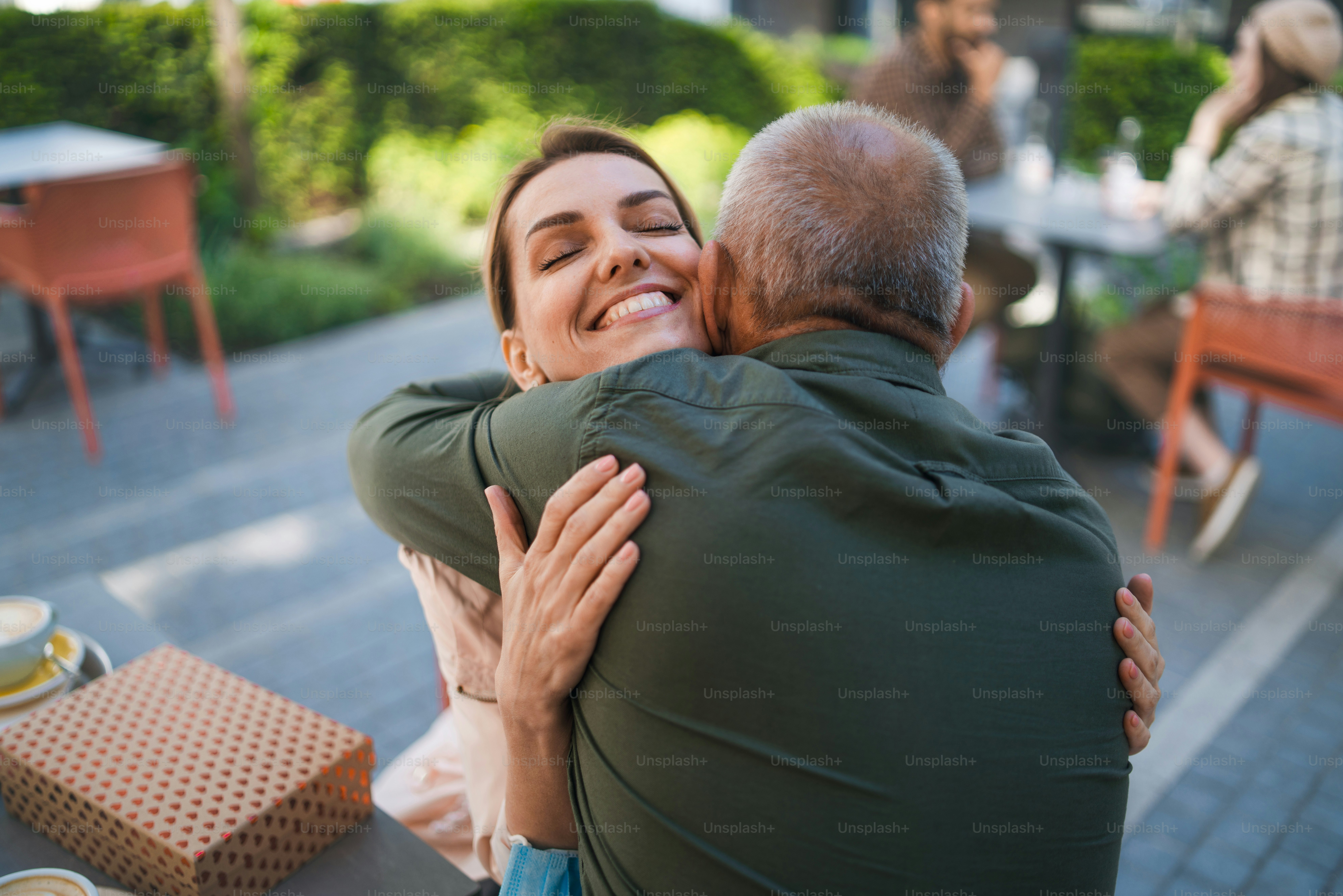 Glückliche Frau umarmt älteren Vater draußen in der Stadt, Leben nach der Covid-19-Impfung und zurück zum normalen Konzept.