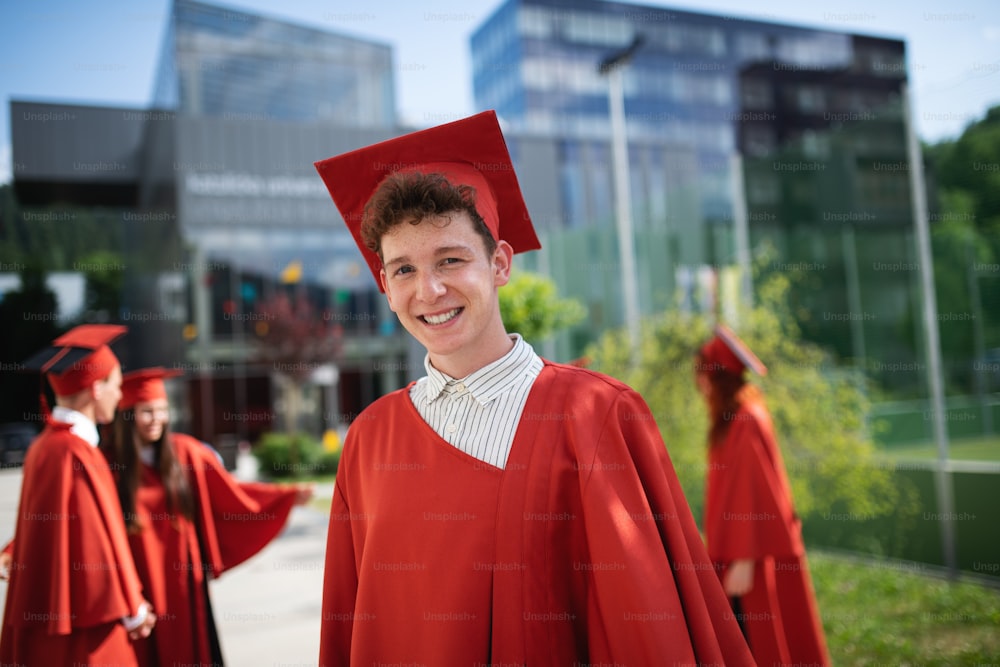 Un ritratto di allegro studente universitario maschio che guarda la macchina fotografica, concetto di laurea.